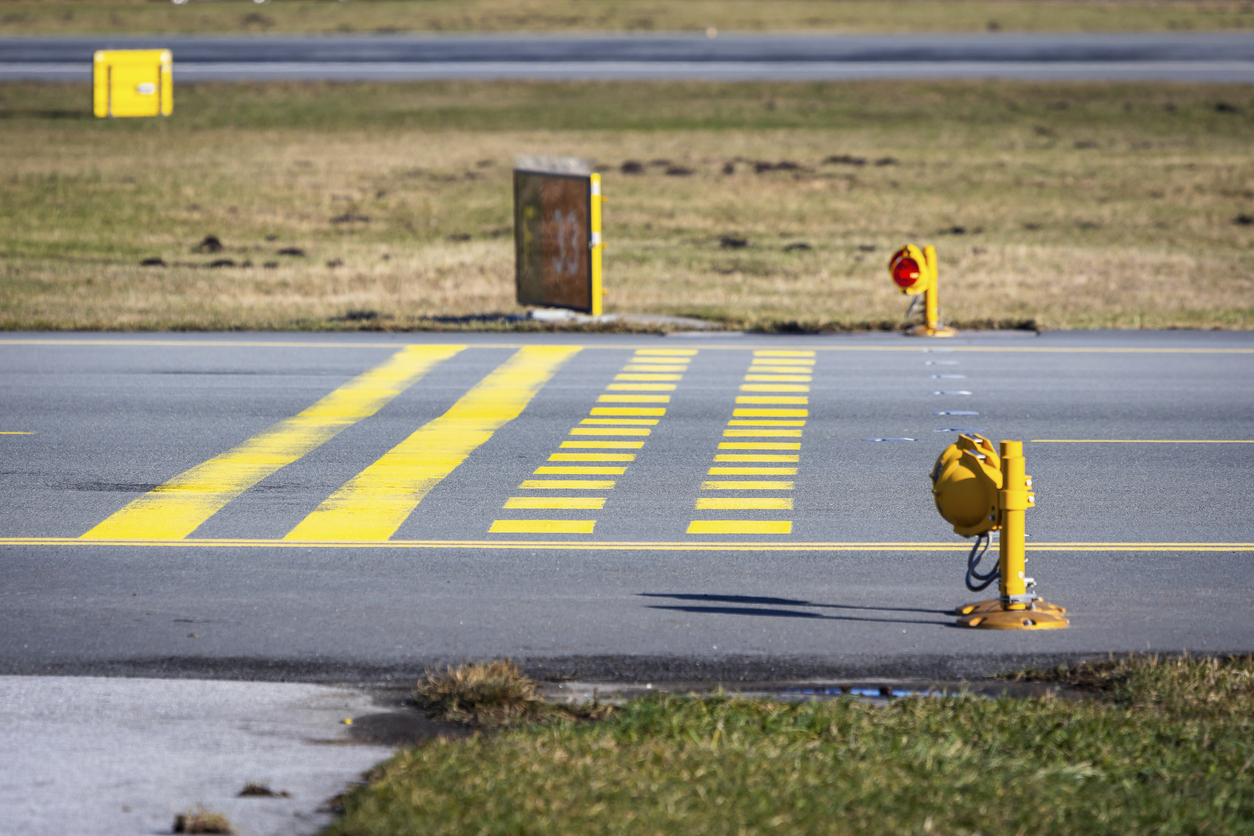 Runway holding point with stop bars and red lights. Airport safety infrastructure.